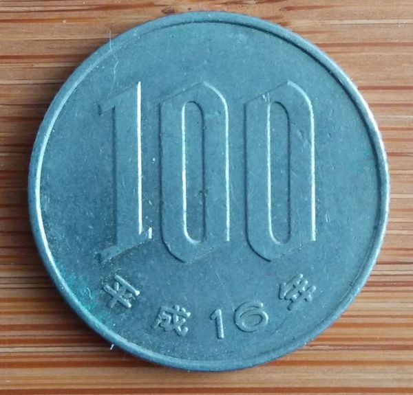 有一枚硬币,正面写着100和平成16年,反面写着