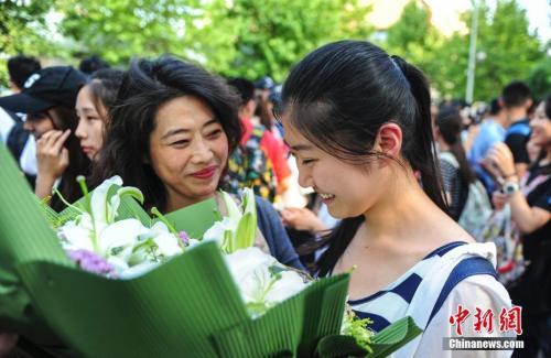 资料图:山东济南众多考生手捧鲜花在家长的簇拥下欢快告别高考.