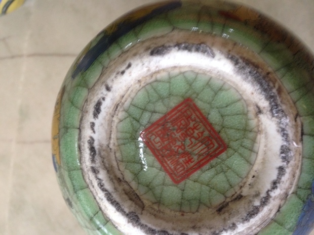 照片中,清乾隆仿哥窑翠青釉地彩绘八仙葫芦瓶是一对臆造的仿品。这对葫芦瓶从形制上与传统葫芦瓶的器型相去甚远,圈口以及上下腹比例严重失调,釉面满贼光,紫口作假明显,铁足忘了做了。釉色深浅不一,开片处未见金丝铁线。彩绘风格现代,人物僵硬,明显是现代印花工艺的产物。胎质松软,底款虽然印的是正确的款识,但是外加双方框纯属画蛇添足。此外,工艺粗糙,做旧手法拙劣等等就不逐一叙述了,关键是,乾隆年间就没有过仿哥窑彩绘葫芦瓶,这完全是作伪者凭空臆造的产物。葫芦瓶因其塑形复杂,制作不易,所以比起其它器型的瓷器来说,葫芦瓶造